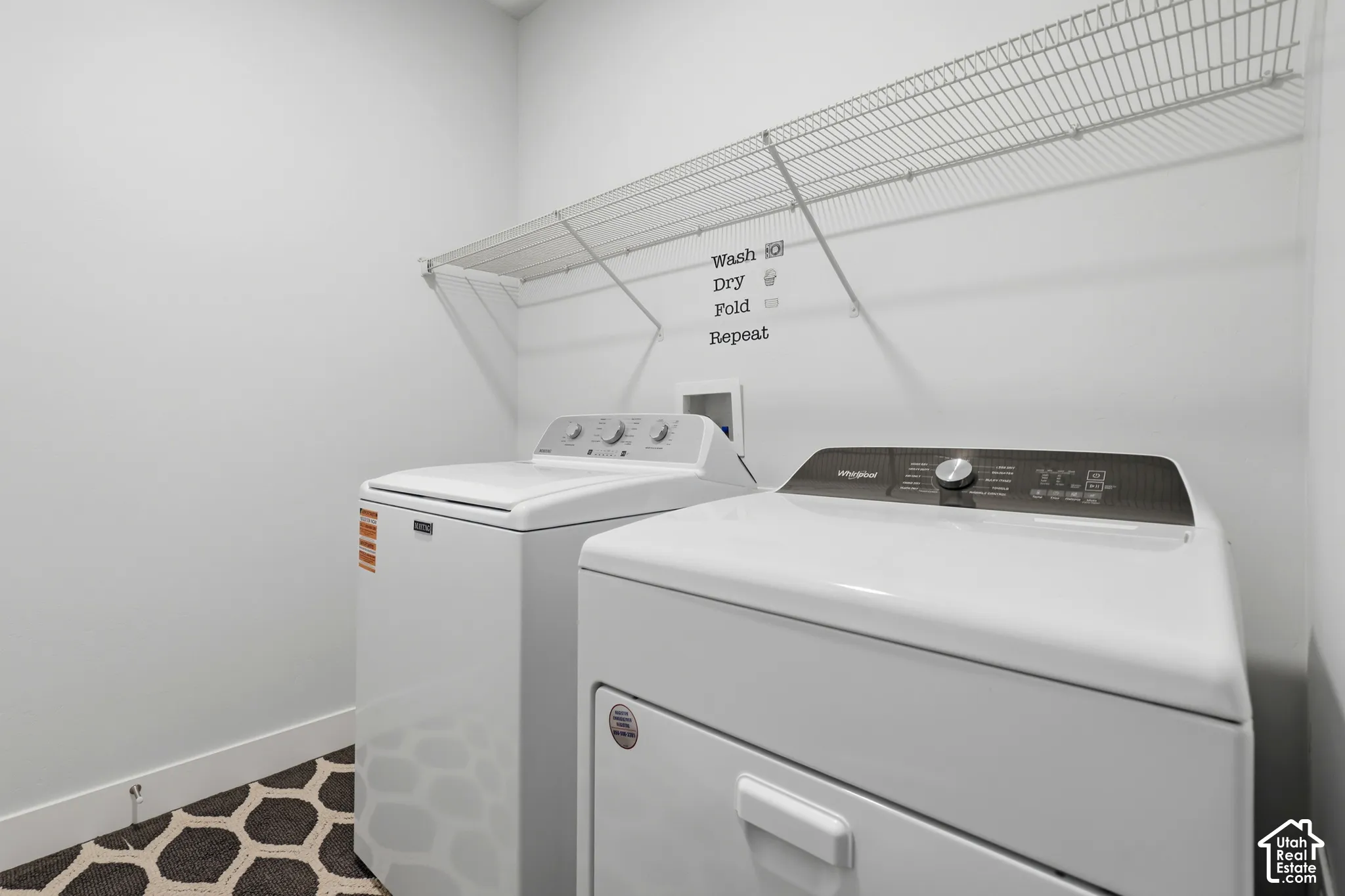 Utility area featuring white washer and dryer, wall-mounted wire shelving, and patterned flooring
