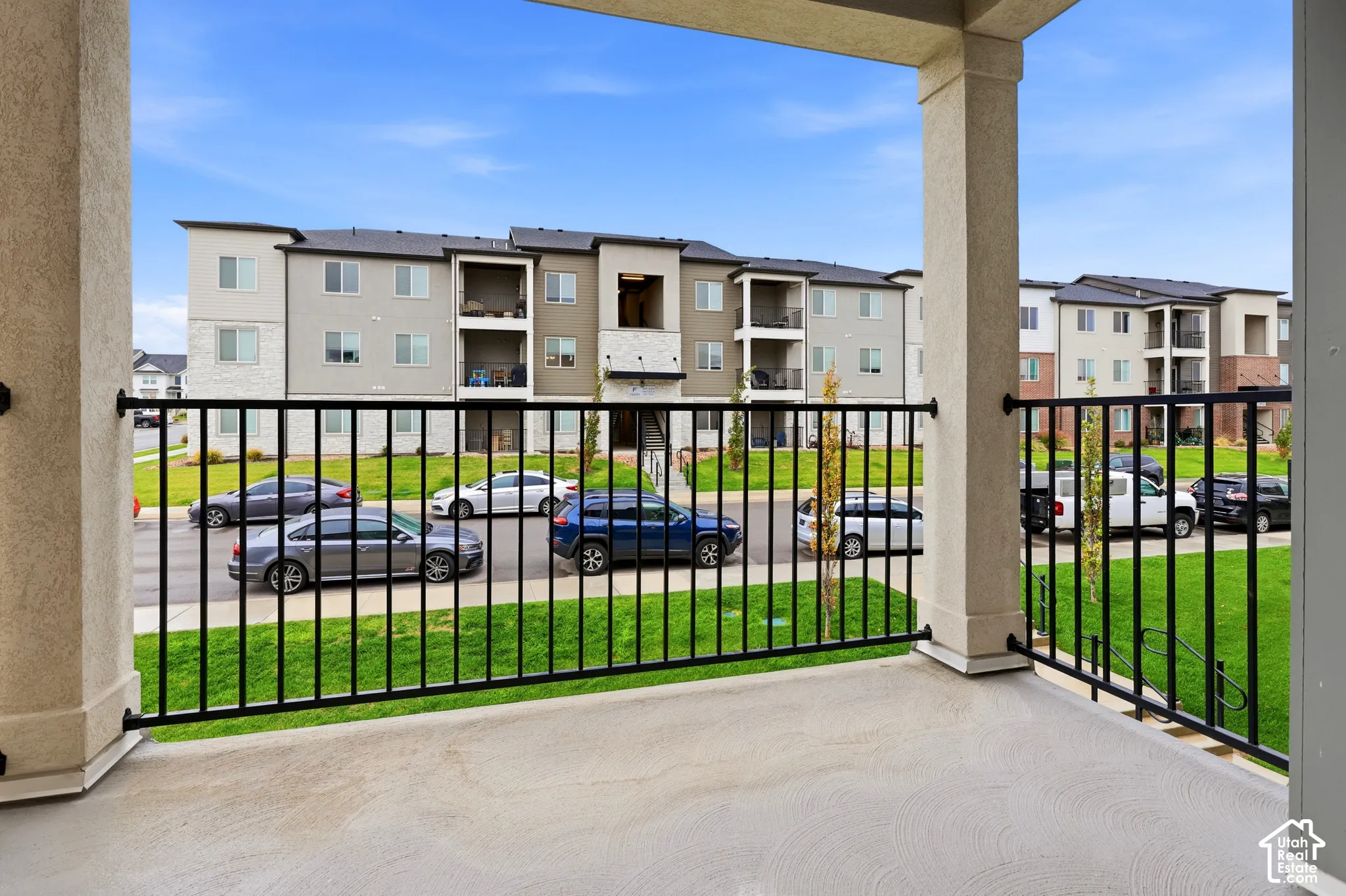 Covered balcony featuring concrete flooring and black metal railing