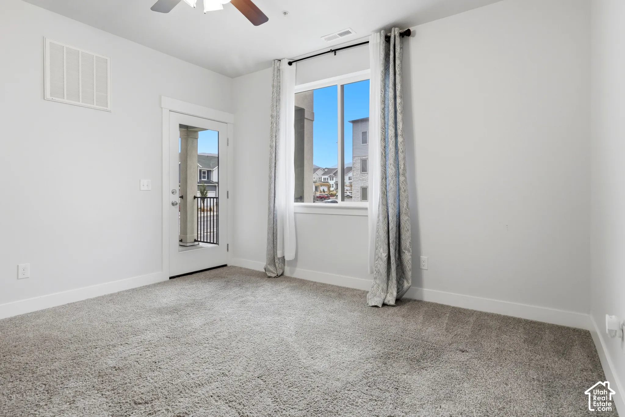 Carpeted flooring, single-pane window, glass-panel exterior door, and ceiling fan with integrated lighting