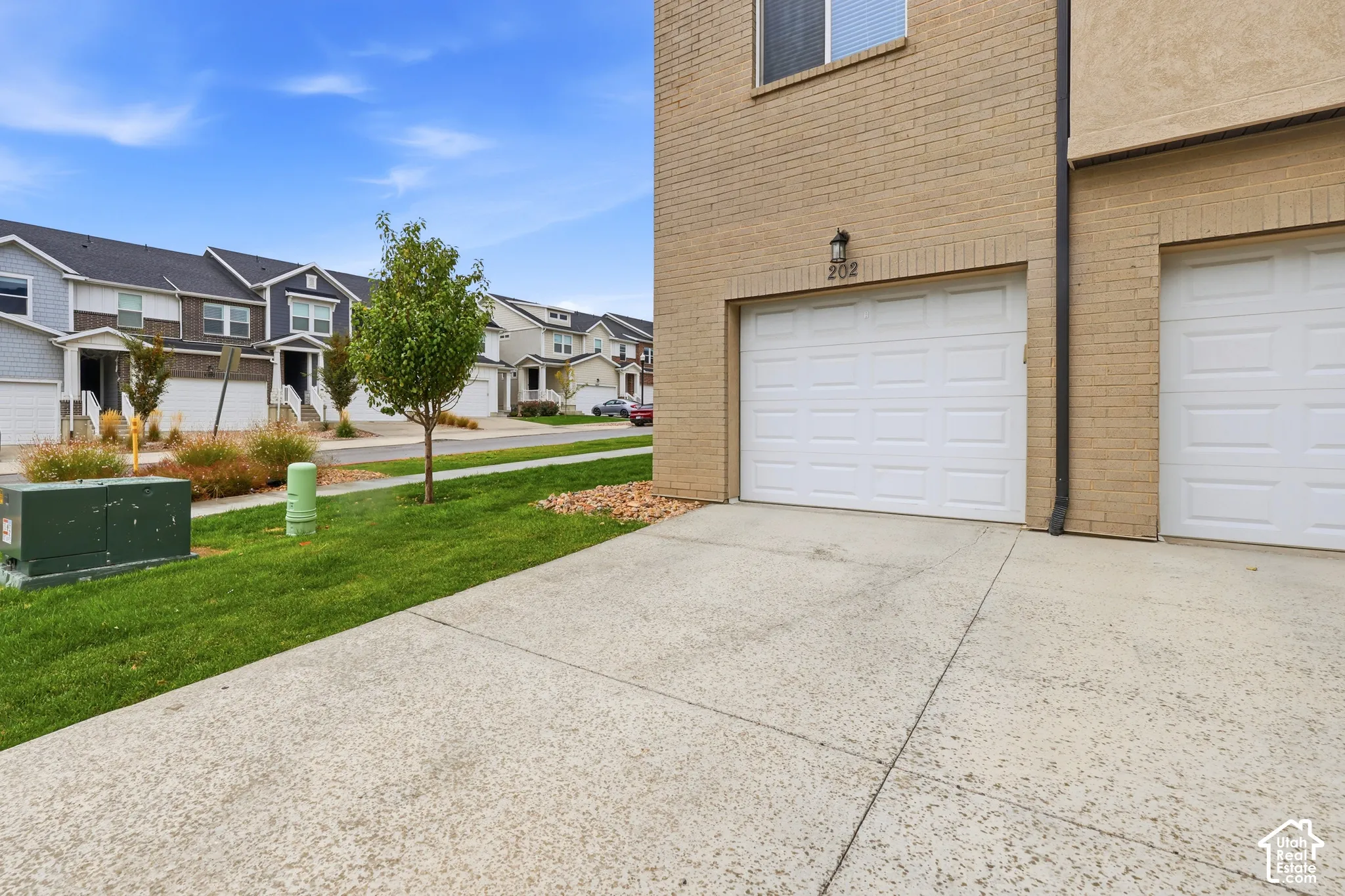 Brick exterior facade featuring a multi-car garage, concrete driveway, and wall-mounted exterior lighting