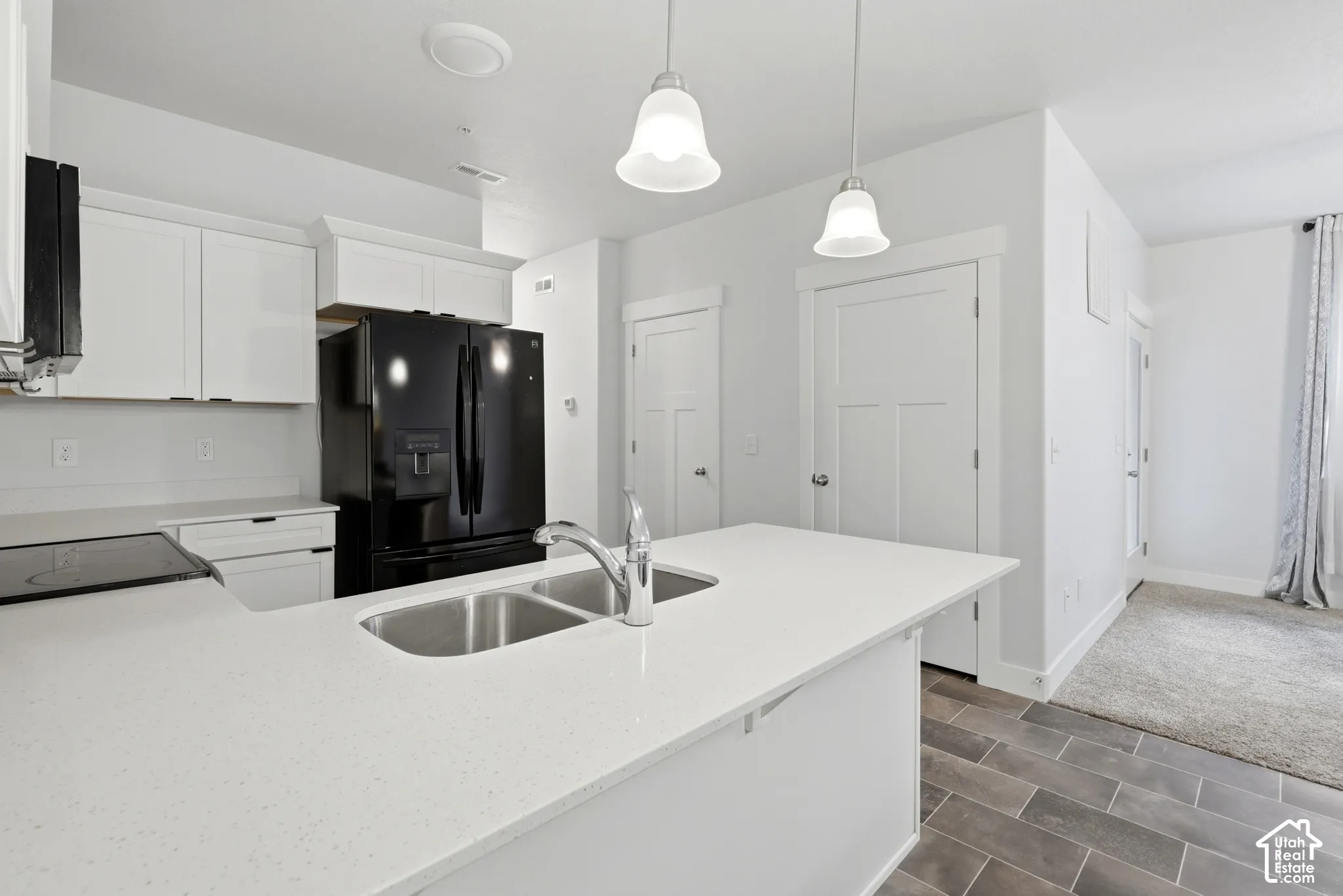 Kitchen featuring white shaker-style cabinetry, quartz countertops, a dual-basin stainless steel undermount sink, pendant lighting, and large-format tile flooring