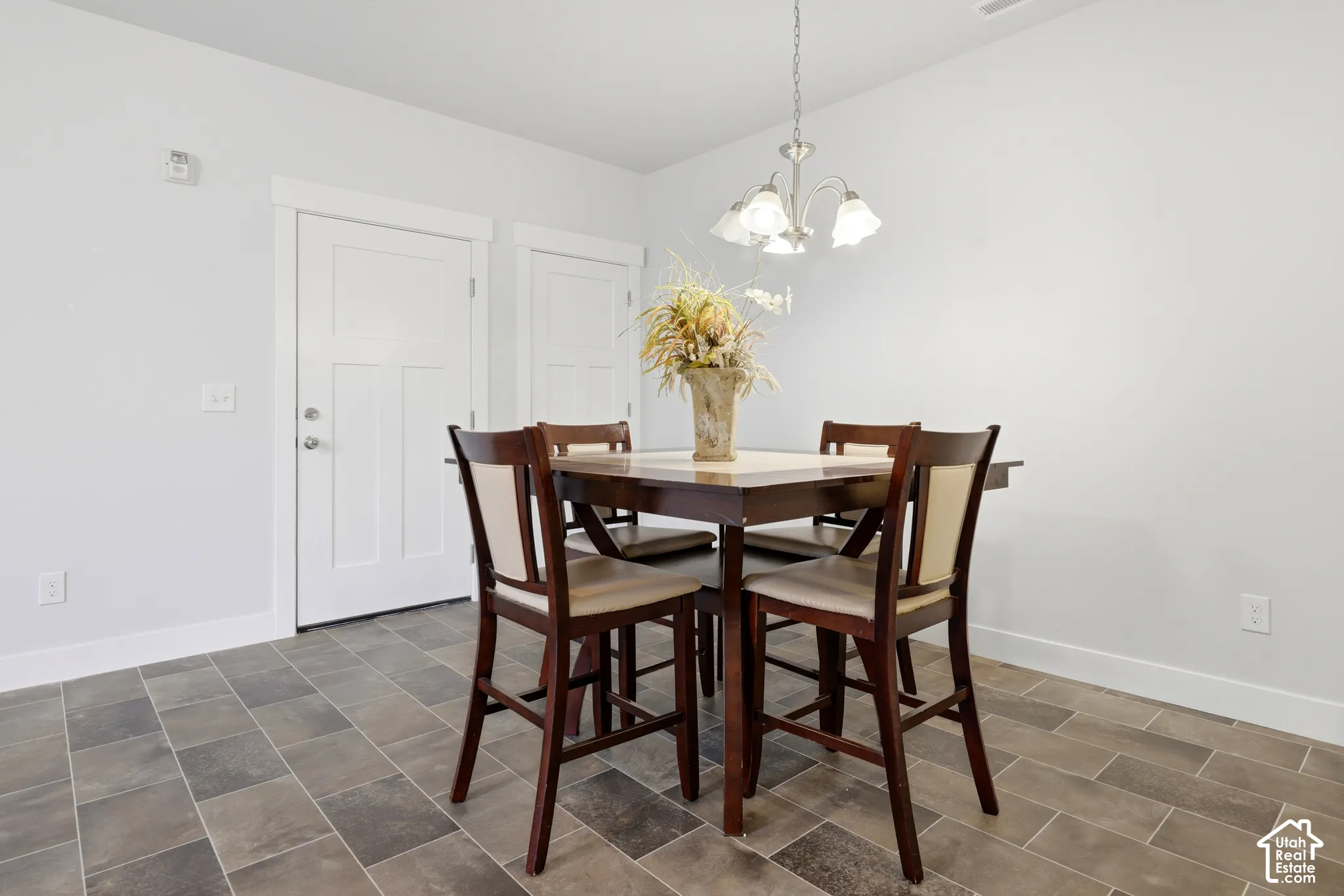 Multi-tonal stone-tile flooring, brushed-nickel multi-light chandelier, and three-panel solid-core interior doors with crisp white trim