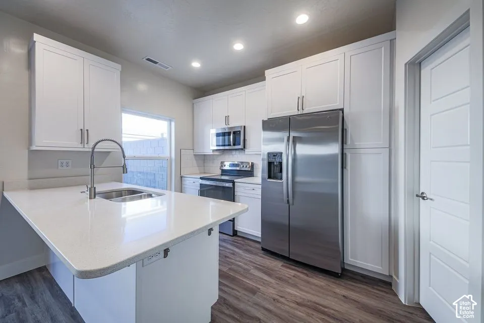 Kitchen featuring white shaker-style cabinetry, a quartz countertop island with a gooseneck faucet, stainless steel appliances, and wood-finish flooring