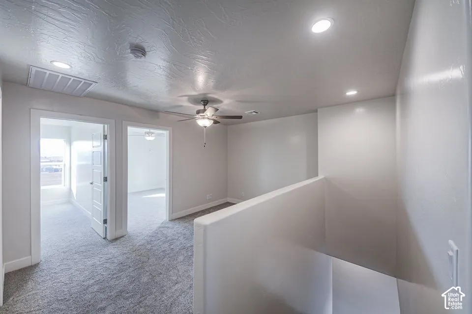 Open loft area featuring neutral carpeting, recessed lighting, a ceiling fan, and textured ceiling finish