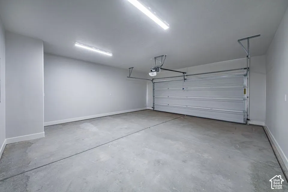 Finished garage featuring neutral wall paint, concrete flooring, dual linear overhead light fixtures, and an automatic roll-up door