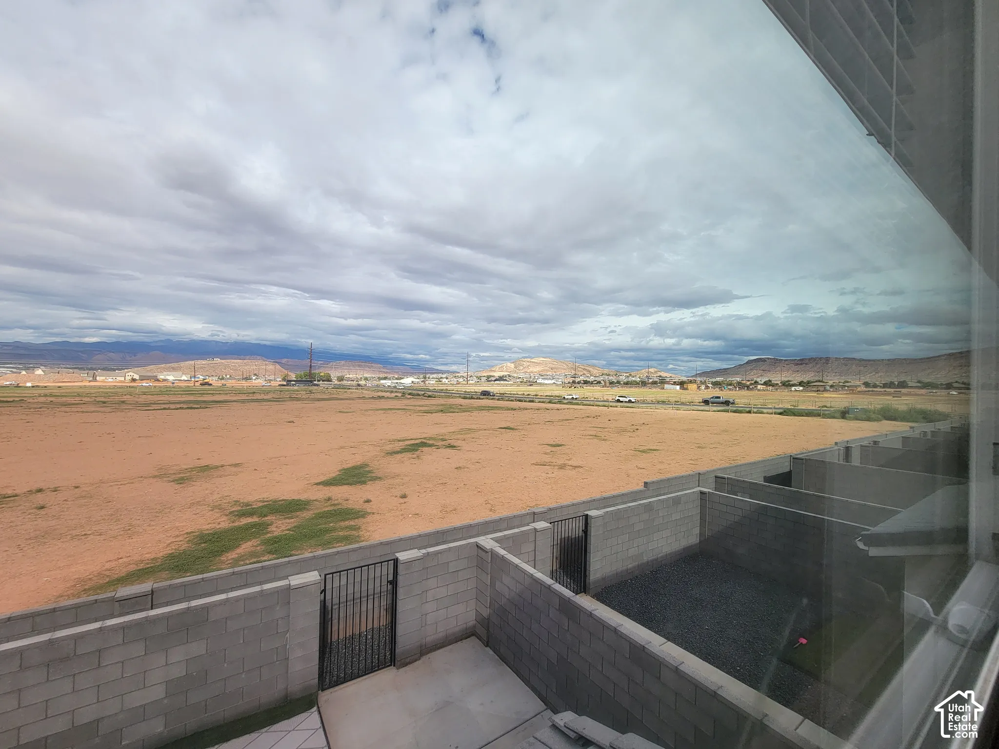 Exterior concrete masonry unit privacy walls, metal access gates, and open desert terrain with distant mountain scenery