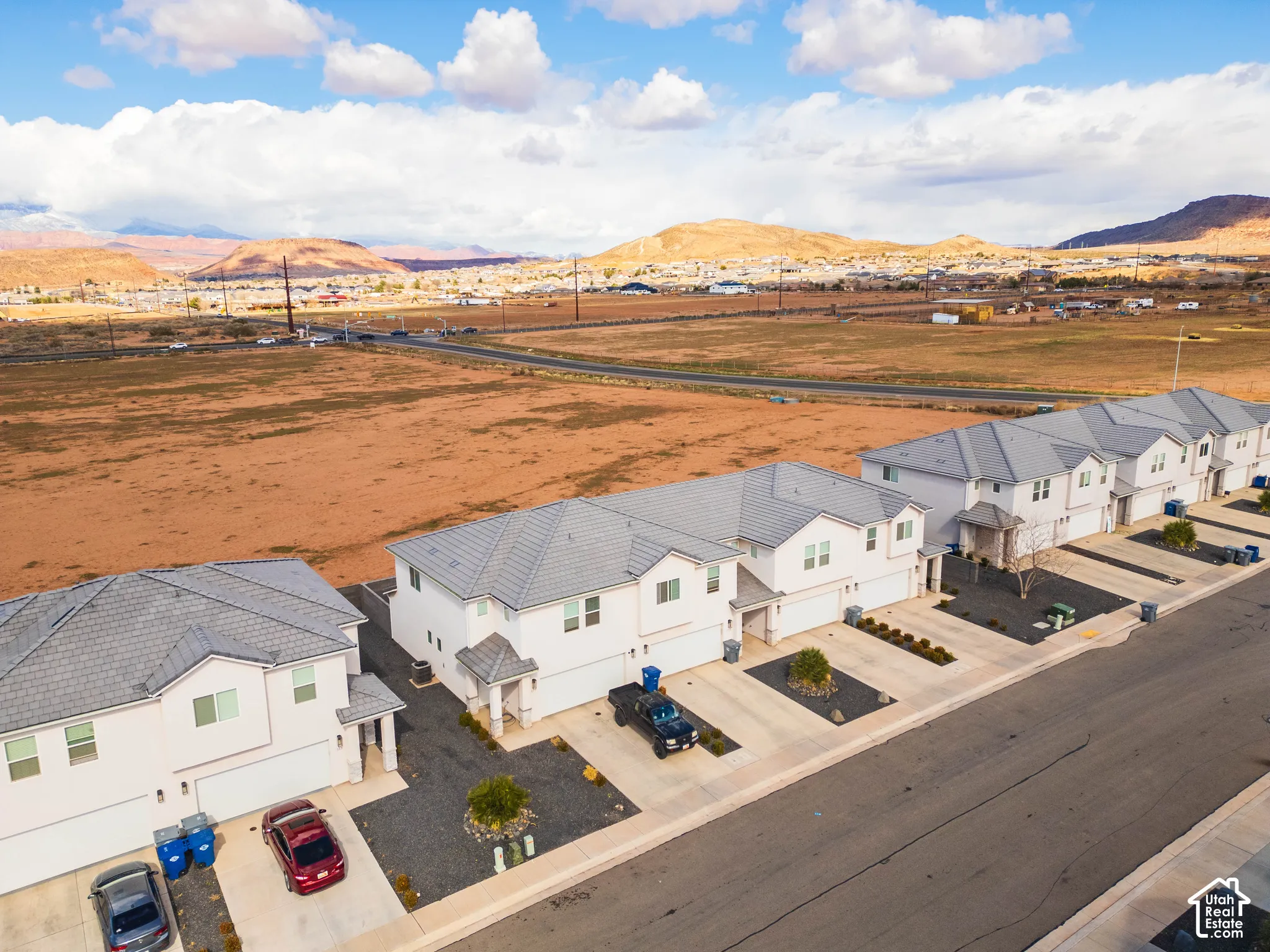 Multi-level residential structures featuring concrete tile roofing, stucco siding, and attached two-car garages, situated against a mountain backdrop