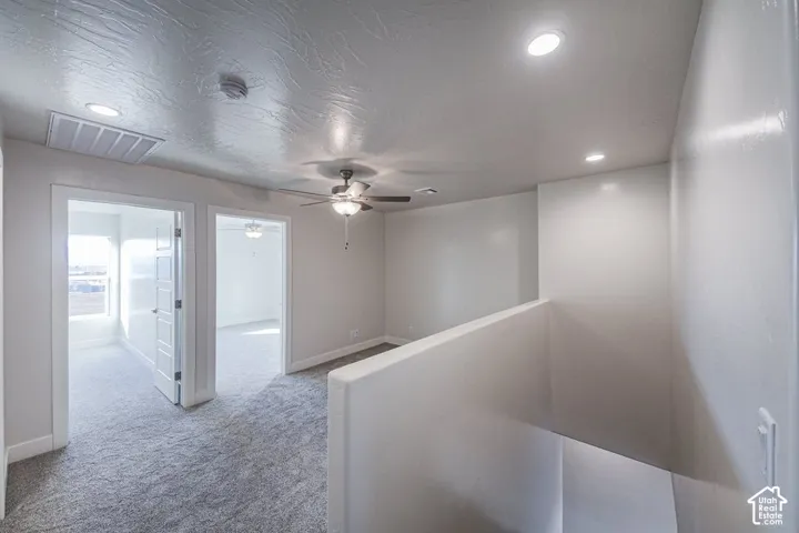 Open loft area featuring neutral carpeting, recessed lighting, a ceiling fan, and textured ceiling finish