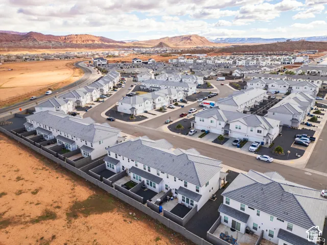 Aerial perspective featuring multi-story residential structures with tile roofing, enclosed private patios, attached garages, and proximity to mountainous desert topography