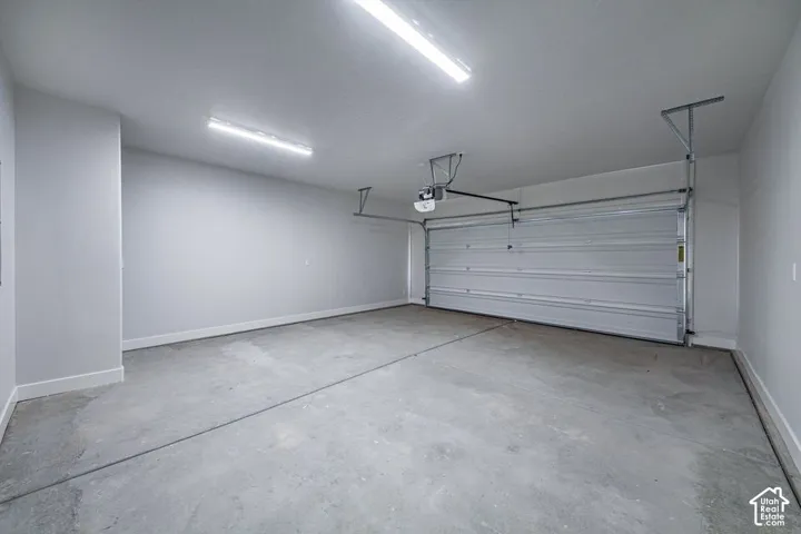 Finished garage featuring neutral wall paint, concrete flooring, dual linear overhead light fixtures, and an automatic roll-up door