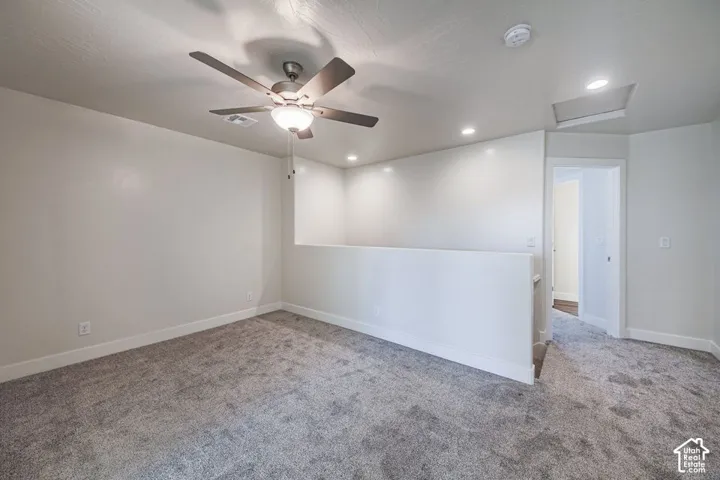 Neutral carpeting, recessed lighting, ceiling fan with integrated lighting, and a half-wall partition