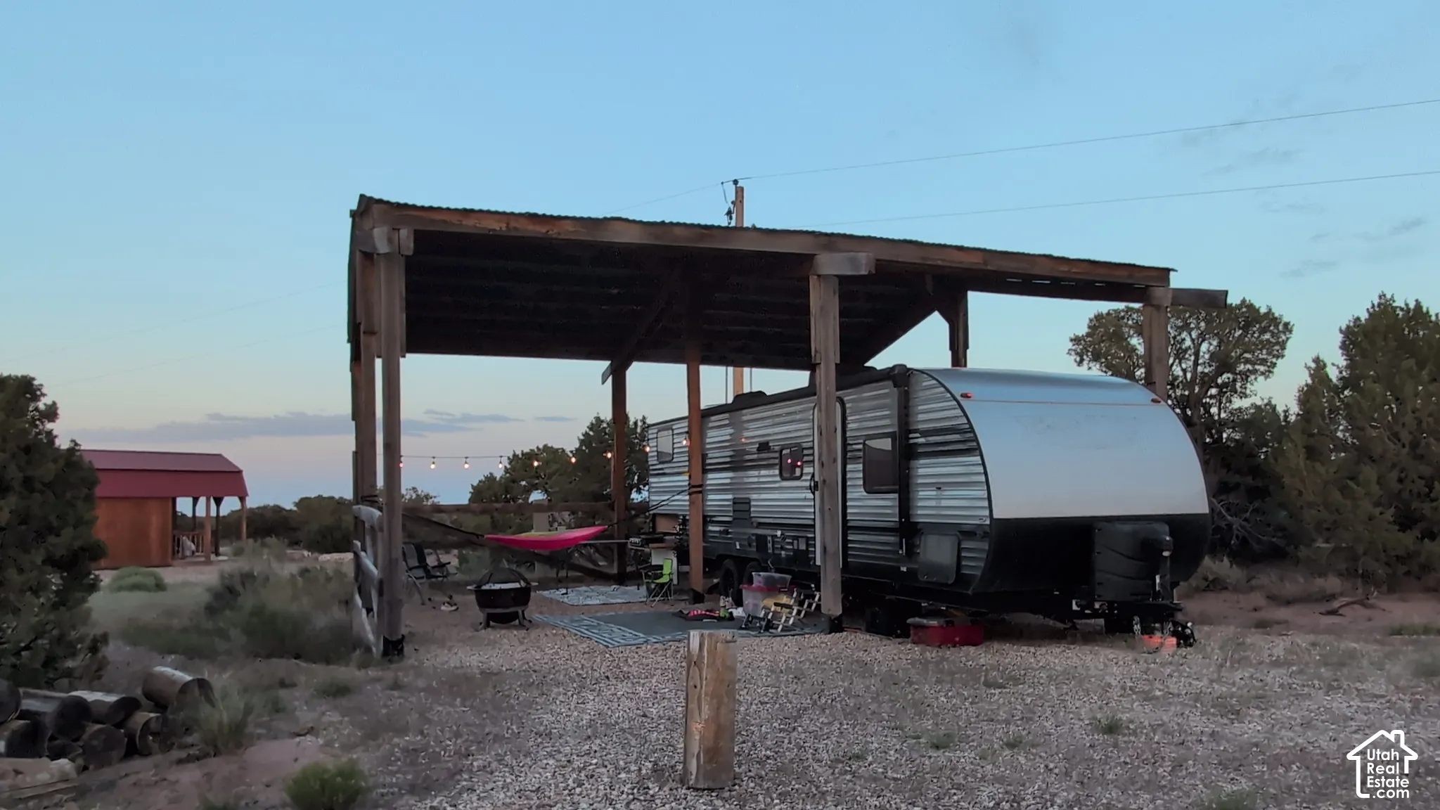 Covered outdoor structure with a timber-frame build and metal roofing, situated on a gravel surface
