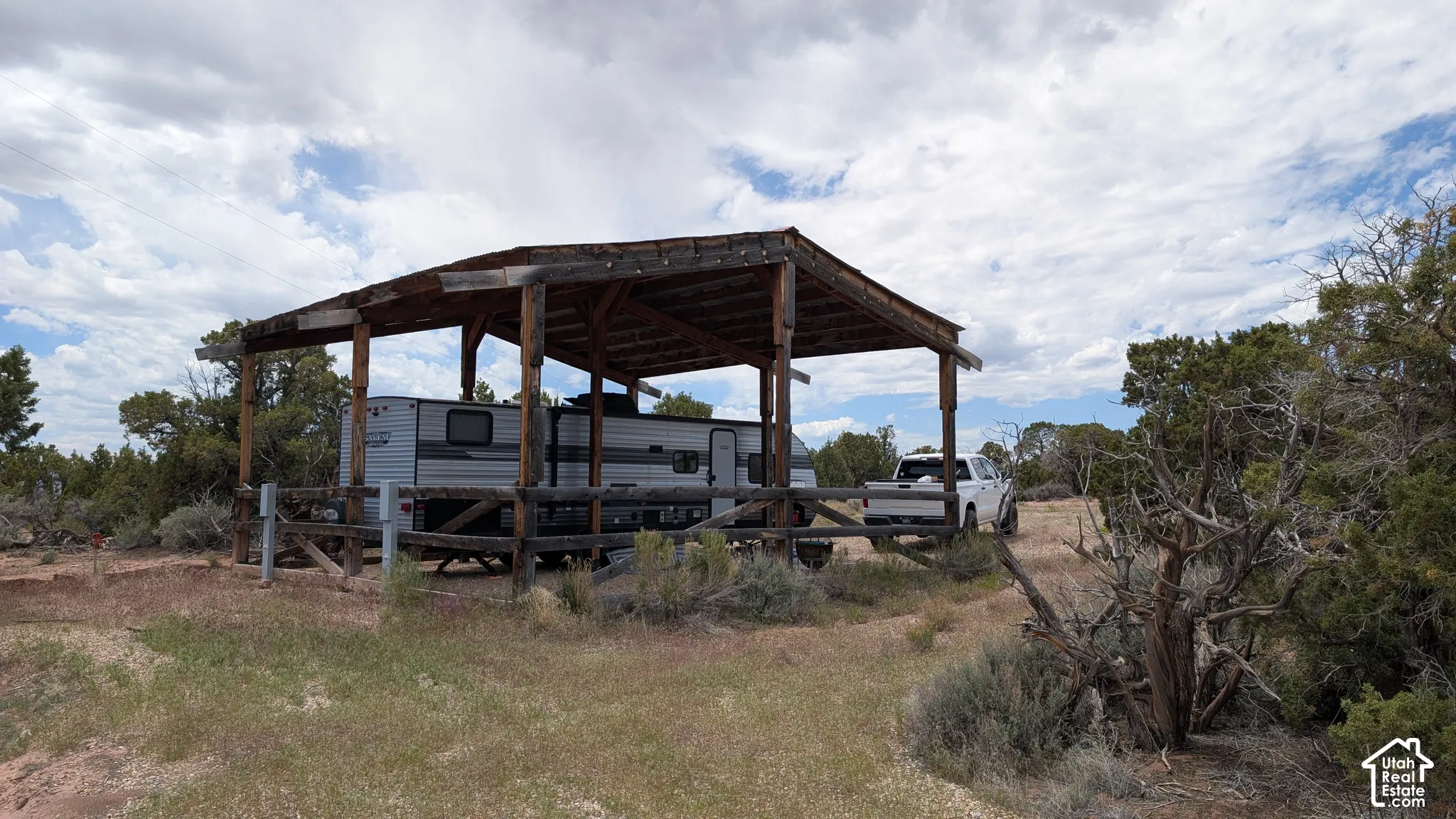 Covered timber-frame structure featuring a wooden post-and-beam support system and perimeter fencing