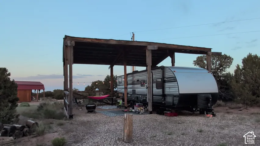 Covered outdoor structure with a timber-frame build and metal roofing, situated on a gravel surface
