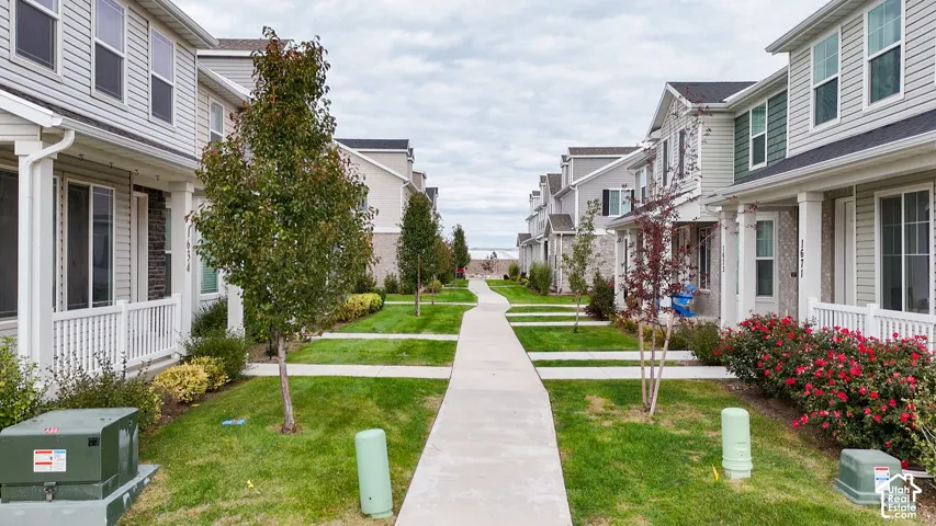 Multi-story residences featuring horizontal siding, brick masonry, front porches with white railings, concrete walkways, and manicured landscaping