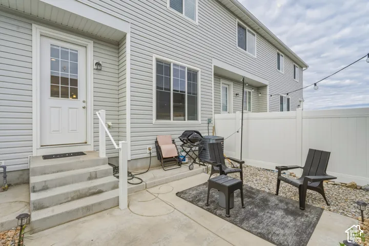 Exterior features include vinyl siding, a private patio, concrete stairs with a metal handrail, and white vinyl privacy fencing