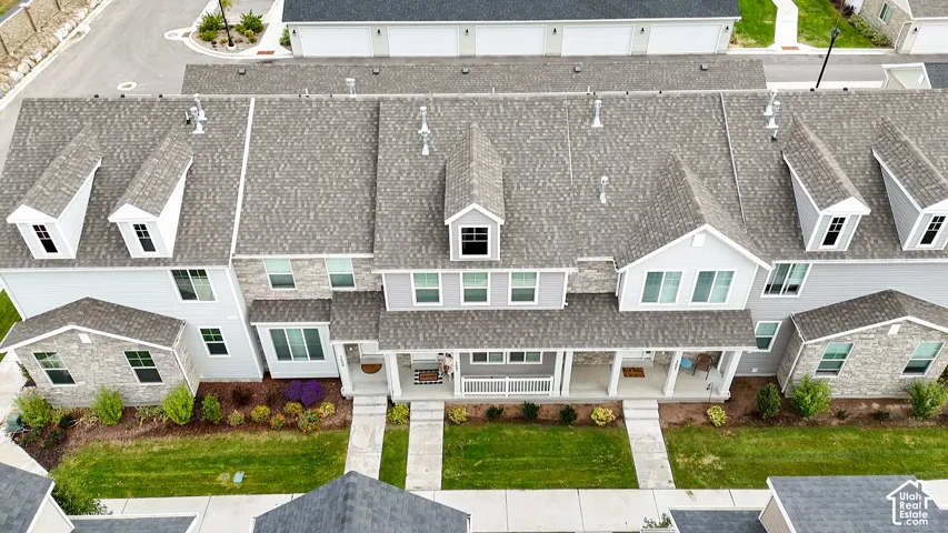 Multi-unit residential structure featuring grey stone veneer and horizontal siding, asphalt shingle roofing, multiple dormer windows, covered porches, and dedicated concrete walkways