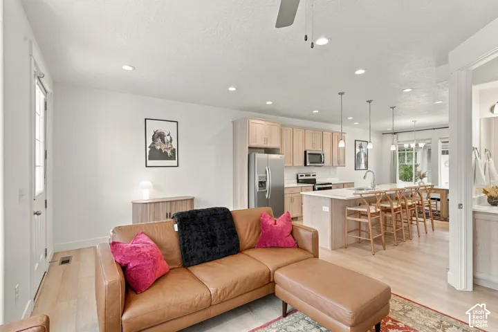Open-concept interior featuring wood-finish flooring, recessed lighting, a center island with pendant fixtures, and light-tone cabinetry