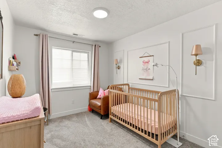 Neutral wall color featuring decorative wall molding, carpeted flooring, and wall-mounted light fixtures