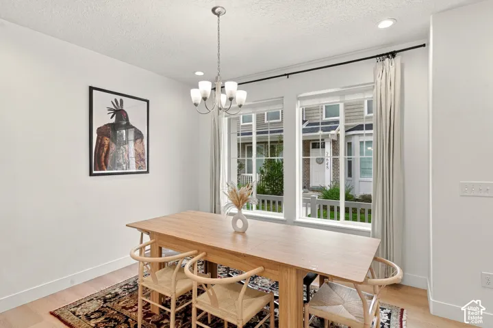 Dining area featuring wood-finish flooring, dual grid-pattern windows, and a multi-arm metallic chandelier