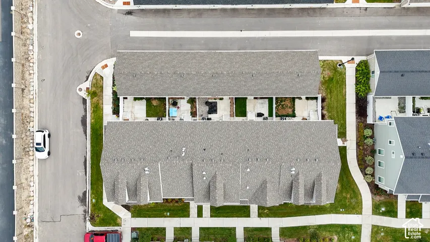 Aerial perspective of residential structure featuring asphalt shingle roofing, concrete sidewalks, maintained lawn areas, and designated surface parking spaces