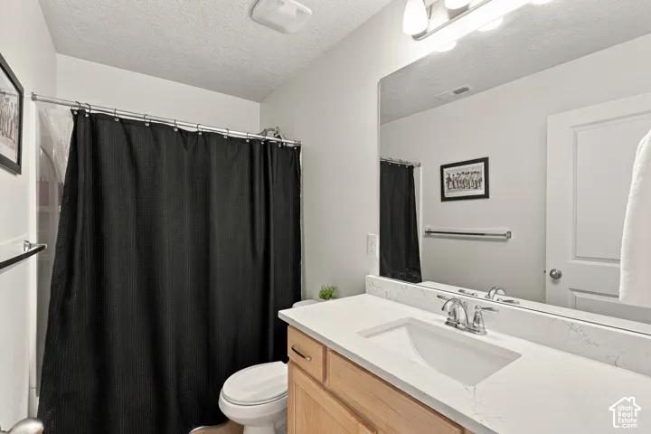 Bathroom featuring a vanity with a light-toned wood finish, a white stone-surface countertop, an integrated rectangular sink, a polished metal faucet, and a large wall-mounted mirror