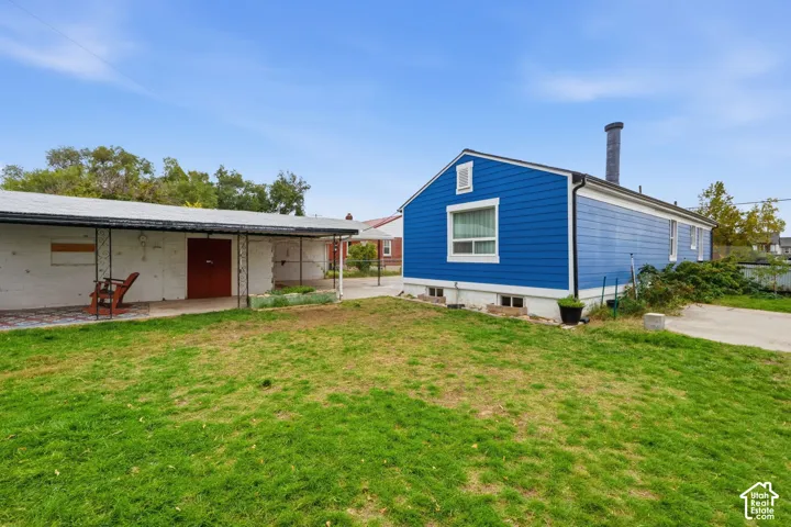 Exterior featuring blue horizontal siding, white masonry structure, covered patio space, and a concrete driveway