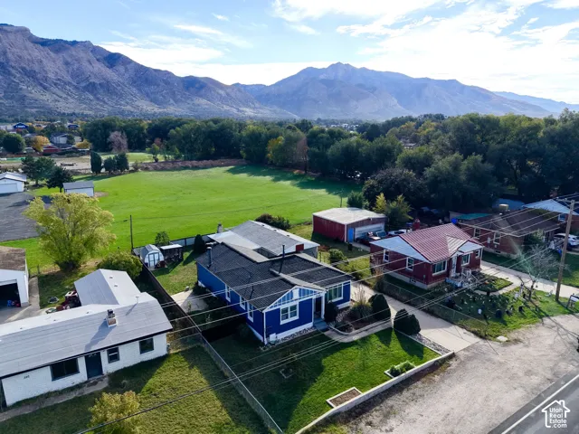 Blue-sided single-story residence featuring a dark shingle roof, front lawn, and prominent mountain backdrop