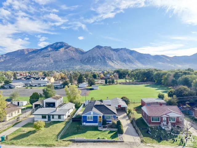 Single-story residence featuring a blue exterior, covered carport, and mountain backdrop