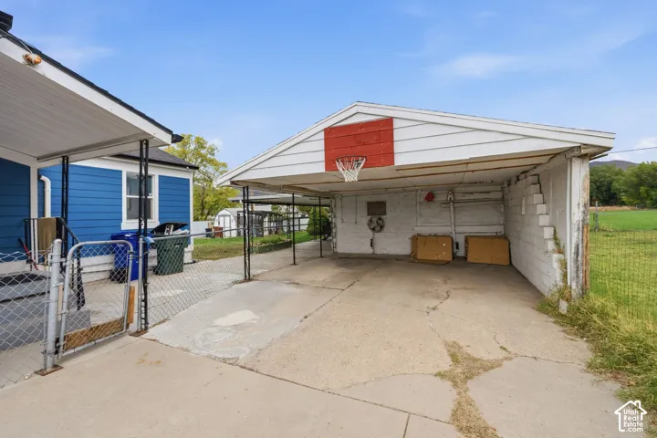 Covered carport featuring a concrete floor, painted masonry walls, and metal siding exterior