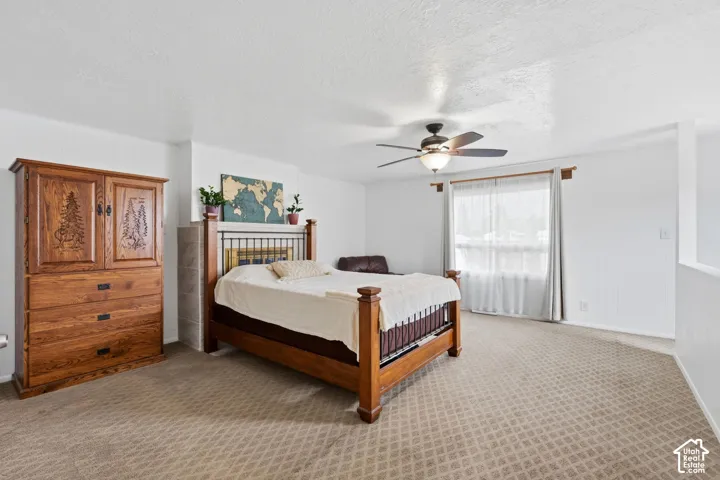 Spacious interior featuring neutral carpeting, a ceiling fan with integrated lighting, and a window with hardware