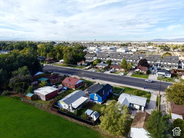 Aerial perspective of a property featuring expansive open grounds, mature trees, a detached storage structure, and a fenced perimeter