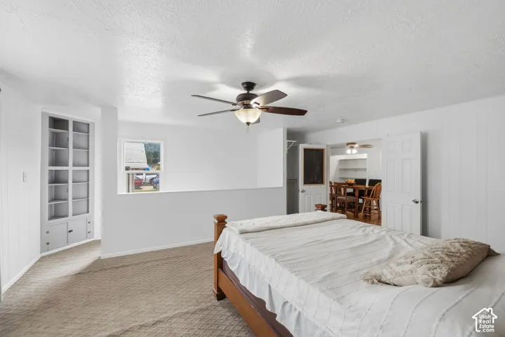 Built-in shelving, carpeted flooring, ceiling fan with integrated lighting, and white paneled walls