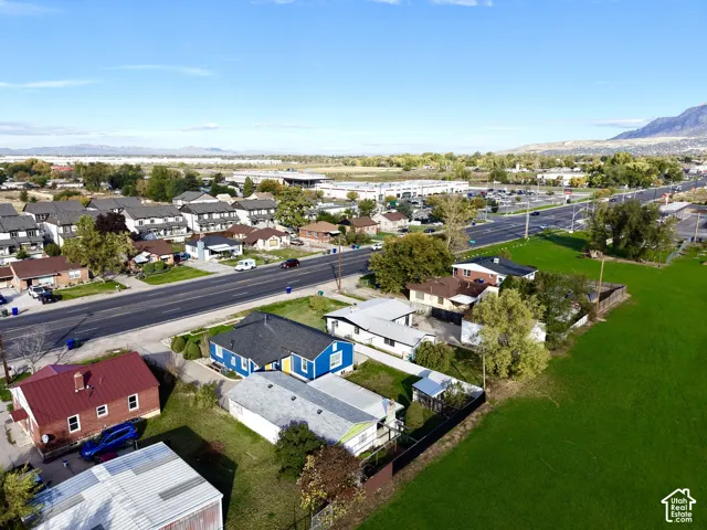 Aerial perspective of the property featuring a blue exterior, asphalt shingle roofing, and mountain backdrop