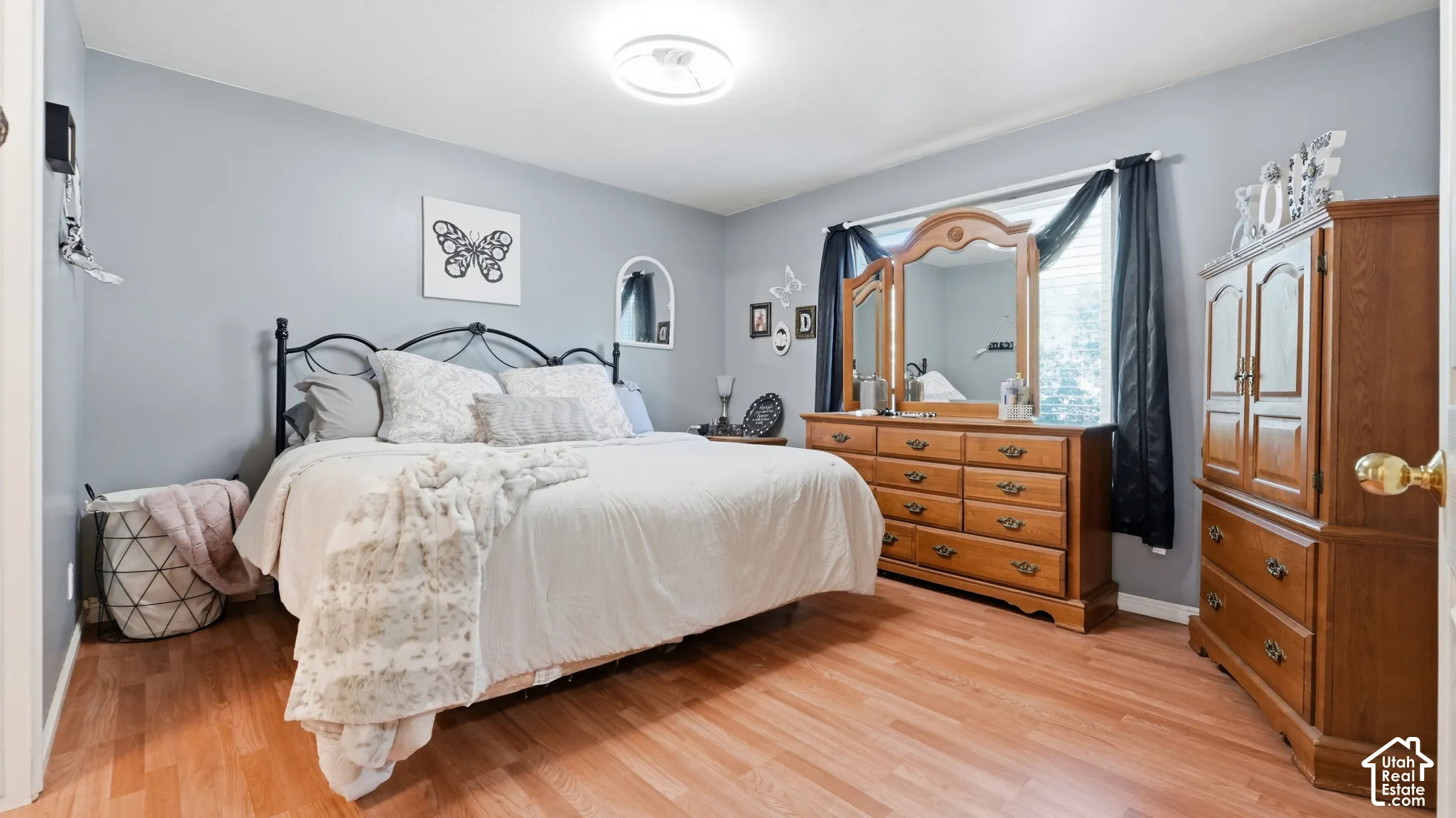 Bedroom featuring wood-finish flooring, a large picture window, and a modern circular LED flush-mount light fixture