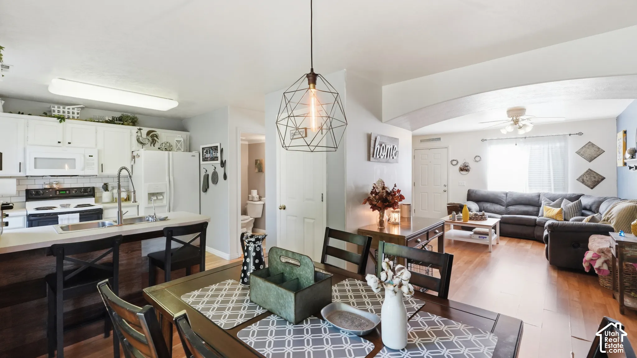 Kitchen featuring white cabinetry, a breakfast bar, and a geometric pendant light, complemented by wood-finish flooring throughout the space