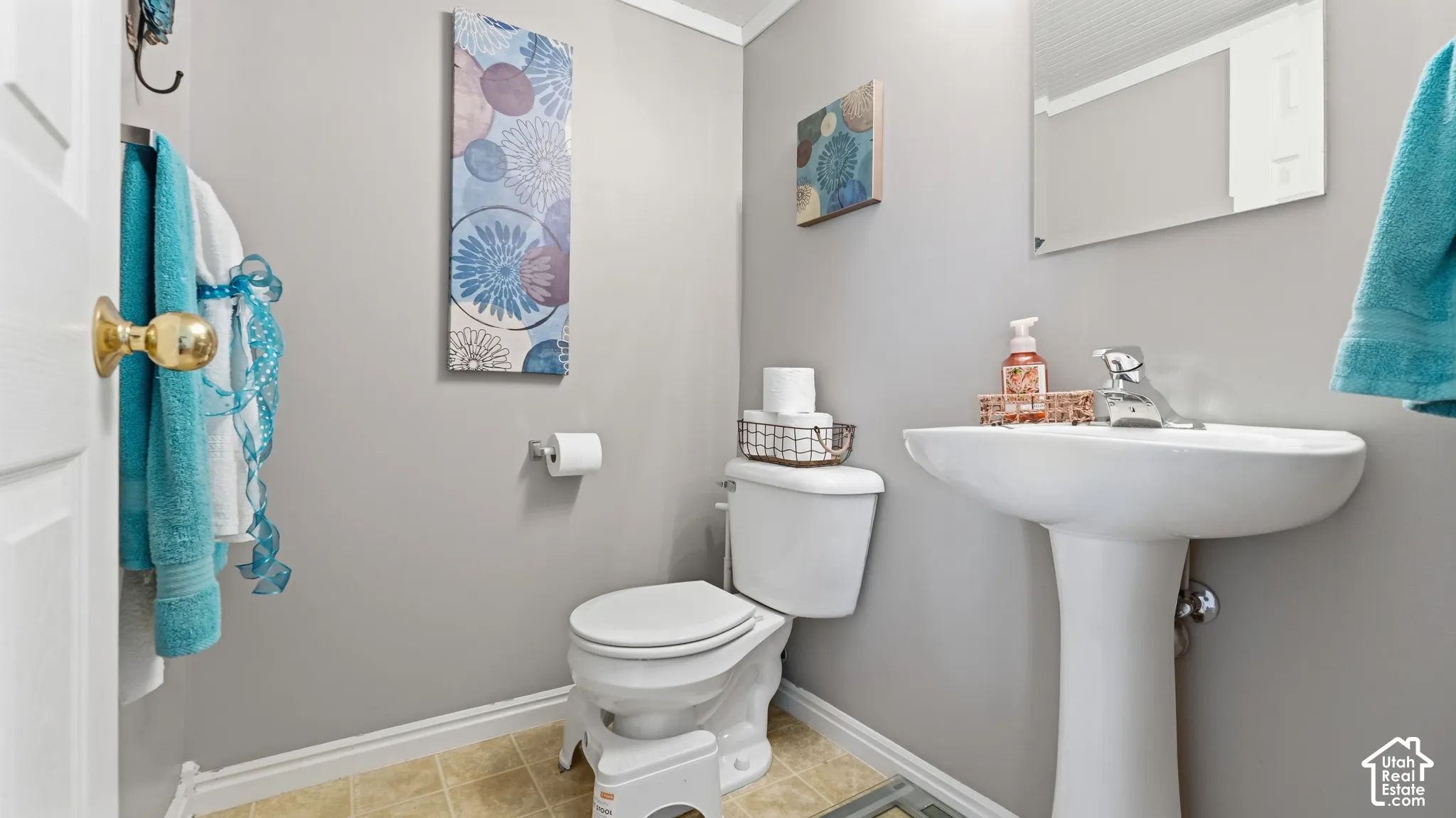 White pedestal sink with a polished chrome faucet, coordinating toilet, and rectangular wall-mounted mirror