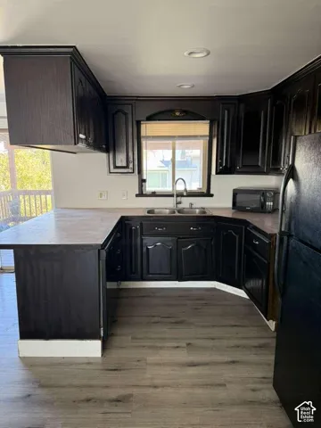 Kitchen featuring dark wood-finish cabinetry, wood-finish flooring, dual-basin stainless steel sink with a high-arch faucet, and recessed ceiling lighting