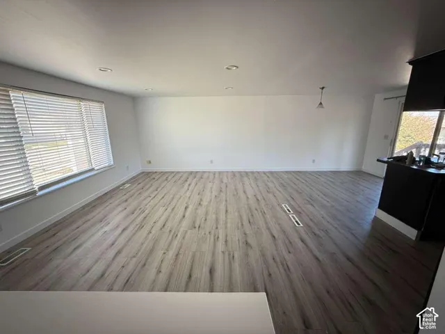 Open-concept interior featuring wood-finish flooring, recessed lighting, neutral wall tones, and horizontal window blinds