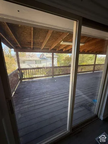 Expansive covered deck featuring wood decking, wood railing, and an exposed beam ceiling