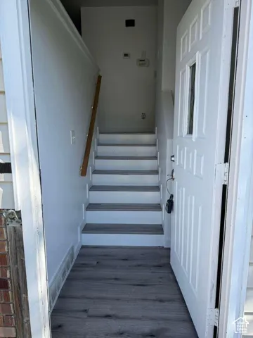 Entryway featuring a paneled door with a glass insert, wood-finish flooring, and a staircase with a wooden handrail