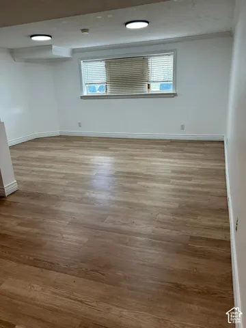Neutral-toned room featuring wood-finish flooring, recessed lighting, and a window with horizontal blinds