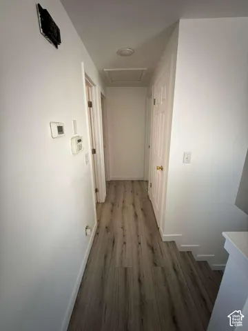 Hallway featuring wood-finish flooring, white walls, and six-panel interior doors