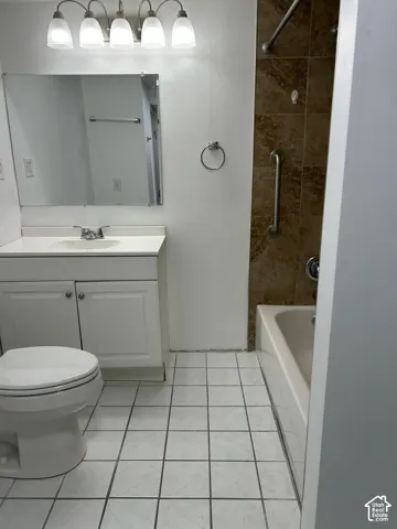 Bathroom featuring a white vanity cabinet with integrated countertop, five-light fixture, tile flooring, and a tub with tiled surround