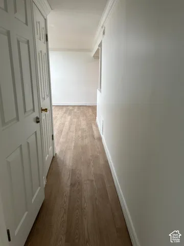 Hallway featuring wood-finish flooring, white panel doors, and neutral wall paint
