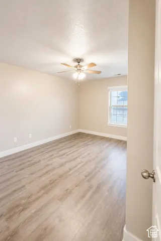 Bedroom featuring wood-finish flooring, a neutral paint palette, a single window, and a ceiling fan with integrated lighting