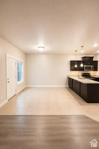 Kitchen featuring dining area, dark cabinetry, granite countertops, stainless steel appliances, recessed ceiling lighting, and pendant fixtures