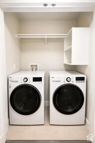 Laundry area featuring dual white front-load appliances, a built-in vertical shelving unit, and a wall-mounted overhead hanging rod