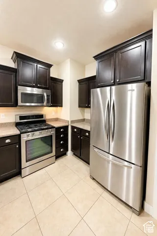 Kitchen featuring dark cabinetry, granite countertops, stainless steel appliances, recessed ceiling lighting, and pendant fixtures
