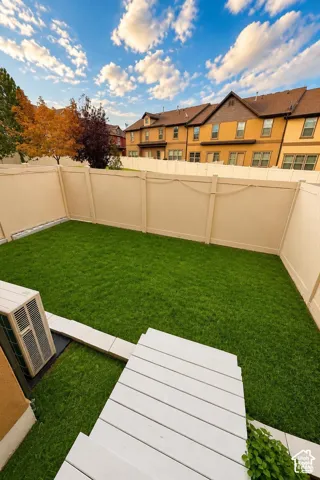 Private backyard featuring a grass lawn, perimeter vinyl fencing, and a white deck. Digitally altered to show with grass.